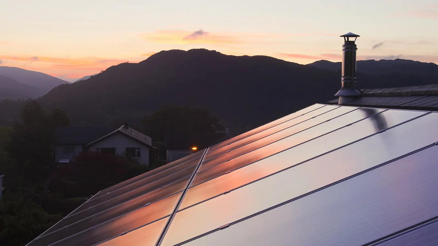 Rooftop solar panels on a two-story home at sunset.