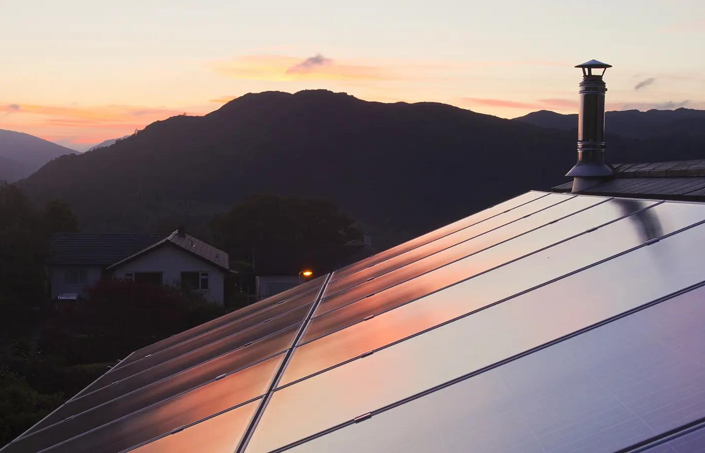Rooftop solar panels on a two-story home at sunset.
